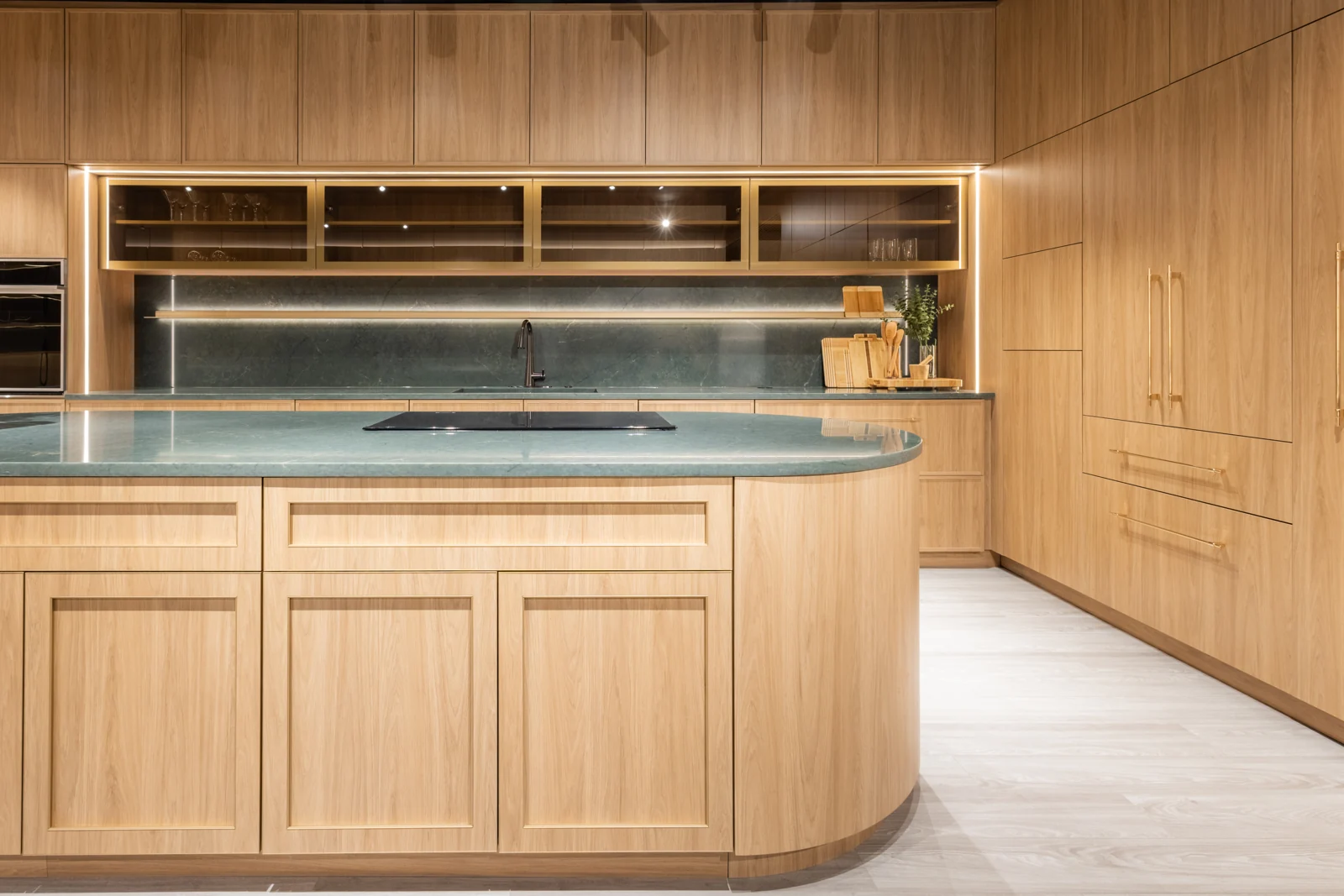 Warm wood cabinetry and a curved kitchen island in the Hommes Design Orlando showroom