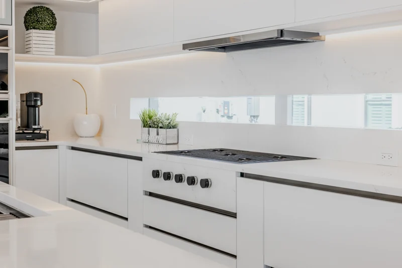 Clean cabinet lines and integrated lighting in a white Hommes kitchen