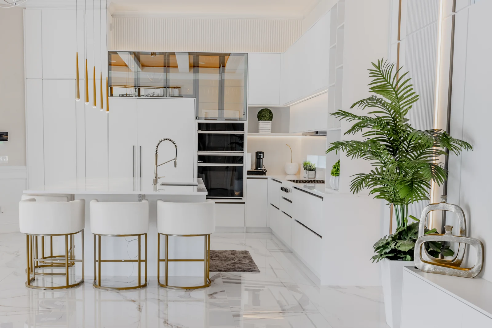 Completed Hommes kitchen with white cabinetry, a generous island and brass pendant lights