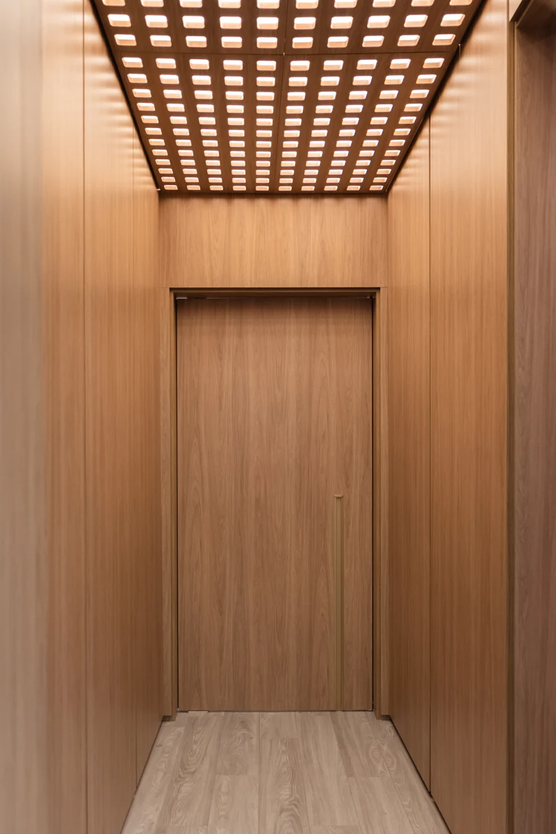Wood-clad hallway and geometric ceiling at the Hommes showroom