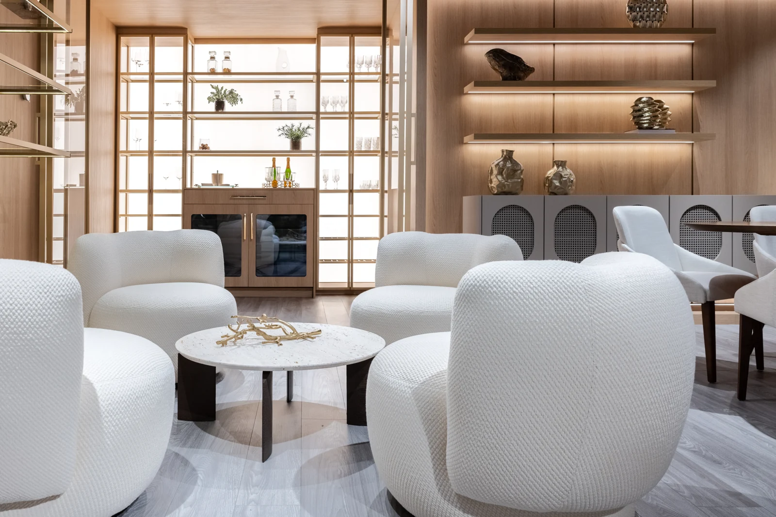 Living and dining displays in the Hommes Design showroom with wood paneling and warm lighting